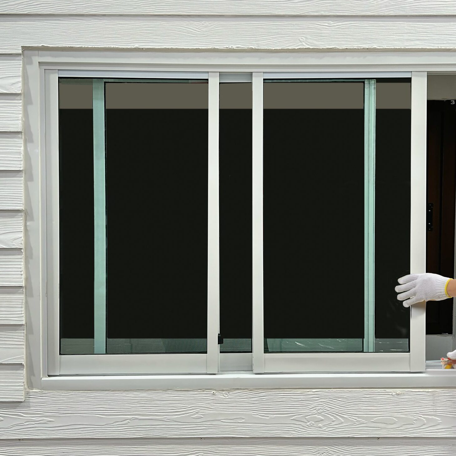 Construction worker repairing the sliding window on artificial woods siding.